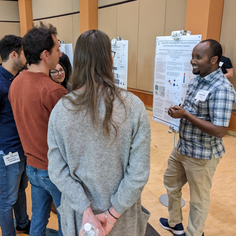 A postdoc discusses his research with others at a poster session